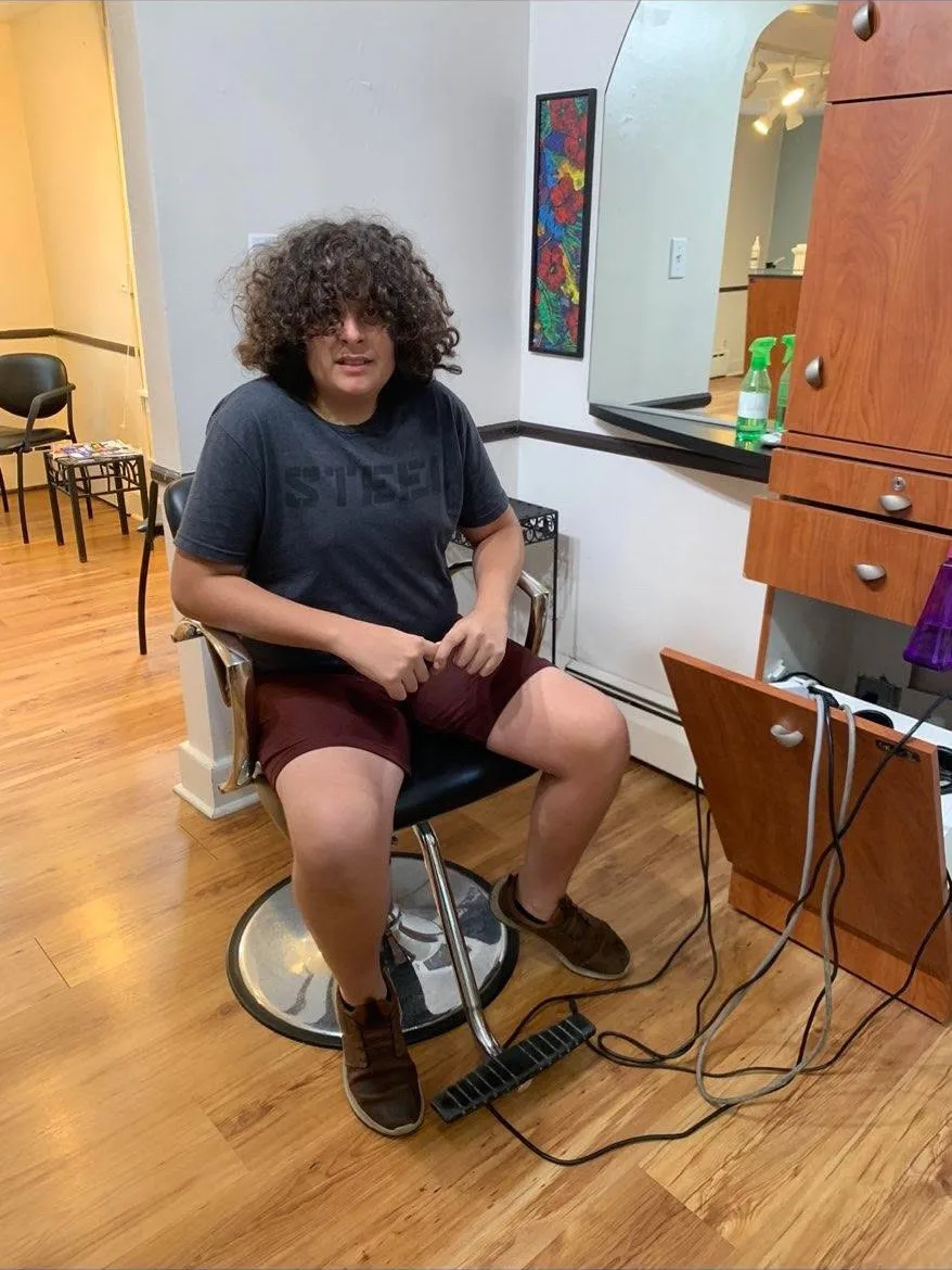George at the start, sitting in a barber chair with long hair and a loose t-shirt