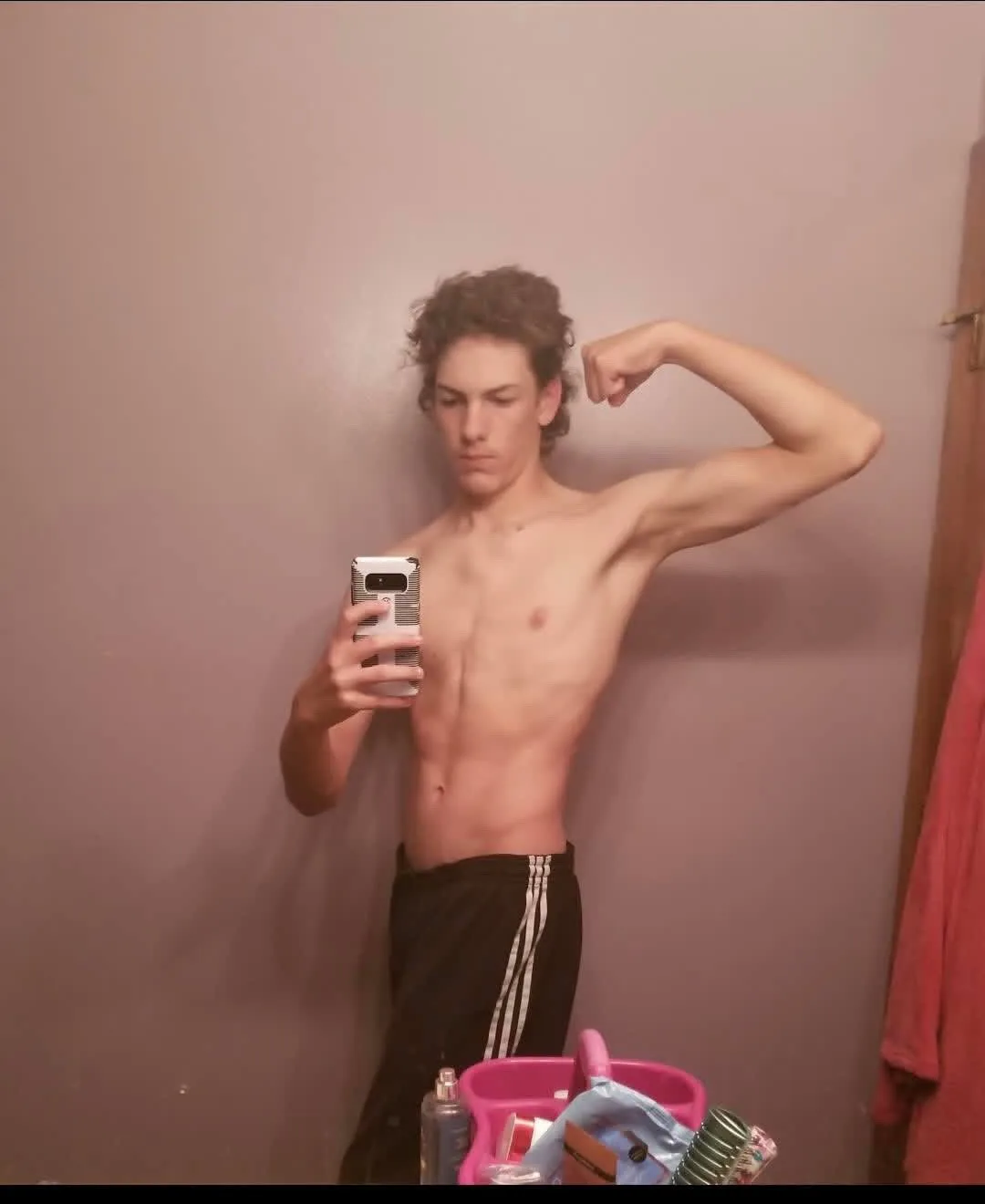 Sam in a bathroom mirror at the start, shirtless, flexing his left arm